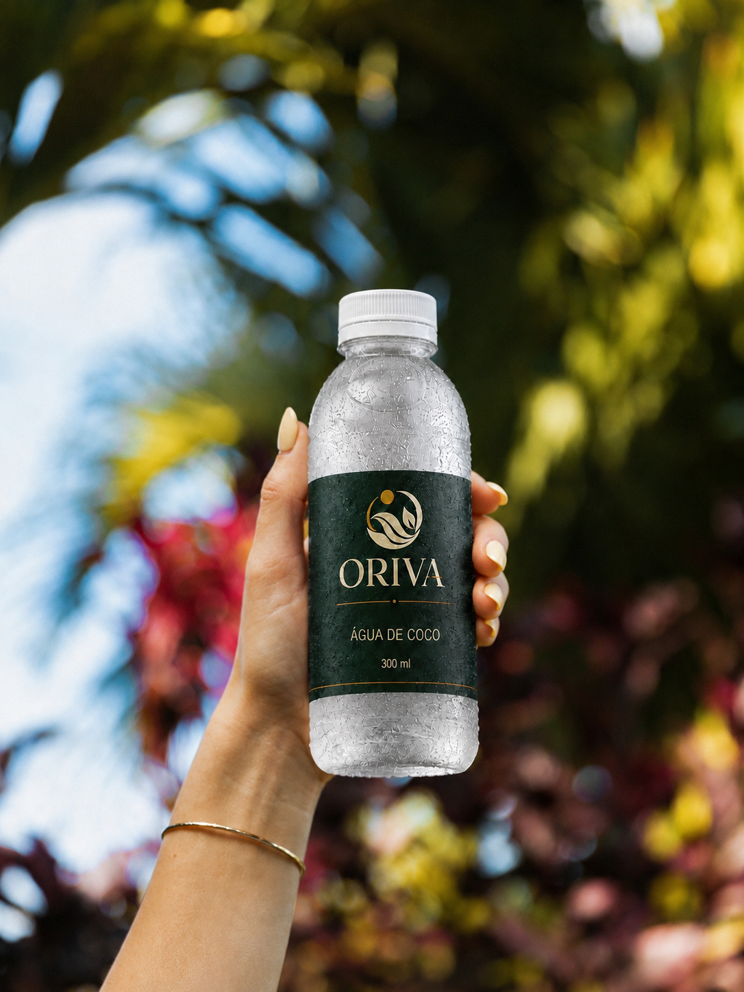 Água de coco Oriva em garrafa com rótulo verde e dourado sobre folhagem